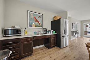 Dallas apartment for rent - A kitchen with a black fridge, wooden cabinets, and a painting of a rooster on the wall.