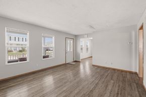 St. Clairsville apartment for rent - A spacious room with wooden floors and white walls, featuring two windows with pictures on them.