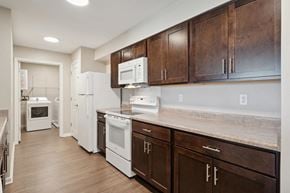 Wilton apartment for rent - a kitchen with white appliances and wooden cabinets