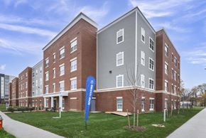 Cleveland apartment for rent - A modern brick building with a blue banner in front that says "Now Hiring".