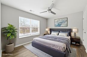 Columbus apartment for rent - A bedroom with a large bed, a ceiling fan, and a potted plant.