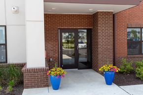 Indianapolis apartment for rent - a brick building with a black door and two blue planters with colorful flowers