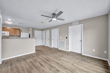 Cleveland apartment for rent - A room with a ceiling fan and a kitchen area with cabinets and a fridge.