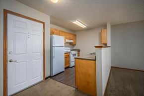 Fostoria apartment for rent - A kitchen with a white refrigerator and wooden cabinets.