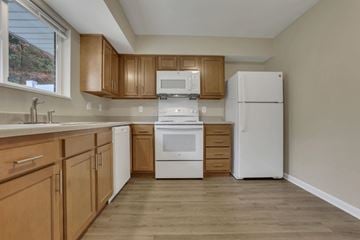 Barnesville apartment for rent - A kitchen with wooden cabinets and white appliances.