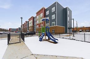 Columbus apartment for rent - A playground with a slide and a fence in front of apartment buildings.