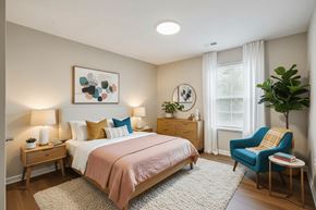 Des Moines apartment for rent - A bedroom with a bed, a chair, and a plant.