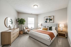 Millersburg apartment for rent - A bedroom with a large bed, a dresser, and a mirror.