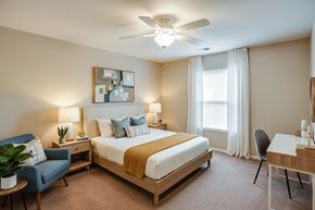 Greeneville apartment for rent - A bedroom with a bed, chair, and a painting on the wall.