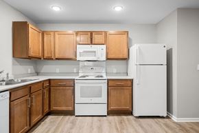 Marquette apartment for rent - A kitchen with wooden cabinets and white appliances.