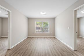 Marquette apartment for rent - A spacious room with light wood flooring and a large window.