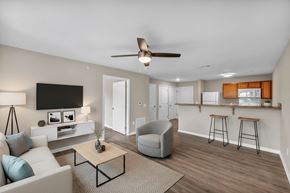 Parma apartment for rent - A living room with a white couch, a grey armchair, a wooden coffee table, and a flat-screen TV mounted on the wall.