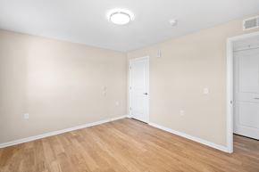 Hebron apartment for rent - a bedroom with white walls and wood flooring and a door