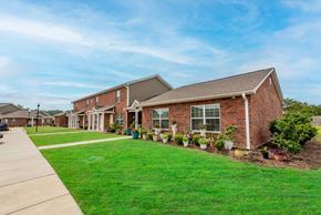 Kingstree apartment for rent - a row of houses on a street with a green lawn and potted plants