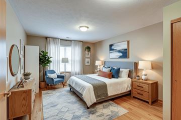 Tiffin apartment for rent - A bedroom with a large bed, a chair, and a painting on the wall.