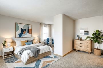 Hartford apartment for rent - A bedroom with a large bed, a nightstand, a dresser, and a plant.