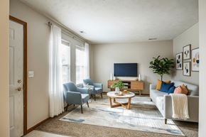 Hartford apartment for rent - A living room with a grey couch, a blue chair, a wooden coffee table, and a flat screen TV.