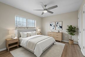 Columbus apartment for rent - A bedroom with a large bed, a ceiling fan, and a plant.
