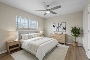 Columbus apartment for rent - A bedroom with a large bed, a ceiling fan, and a plant.