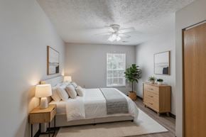 Sycamore apartment for rent - A bedroom with a bed, nightstand, and a plant.