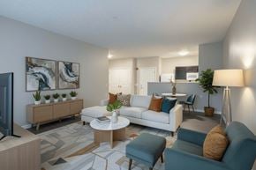 Sycamore apartment for rent - A living room with a white couch, a blue chair, and a television.