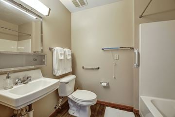 Cadiz apartment for rent - A white toilet sits in a small bathroom with a sink and mirror.