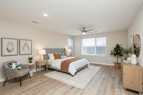 Charlotte apartment for rent - A bedroom with a bed, chair, and a plant.