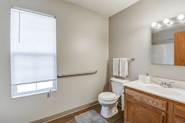 Weirton apartment for rent - A bathroom with a toilet, sink, and window.