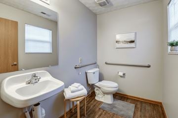 Weirton apartment for rent - A small bathroom with a toilet, sink, and a picture on the wall.