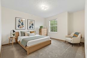 Steubenville apartment for rent - A bedroom with a bed, chair, and two framed pictures on the wall.