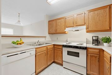 Steubenville apartment for rent - A kitchen with wooden cabinets and white appliances.