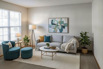Washington Court House apartment for rent - A living room with a grey couch, a blue chair, a small table, and a painting on the wall.