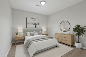 Athens apartment for rent - A bedroom with a large bed, a side table with a plant, and a dresser with a mirror.