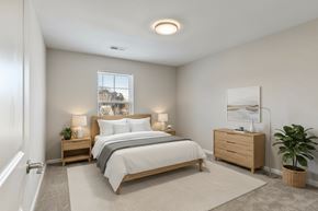 Hopkinsville apartment for rent - A bedroom with a large bed, nightstands, and a plant.