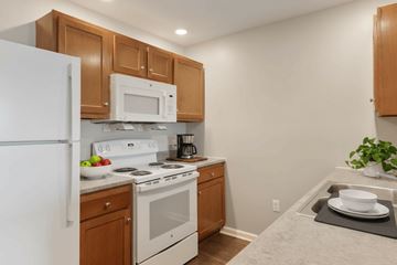 Hopkinsville apartment for rent - A kitchen with white appliances and wooden cabinets.