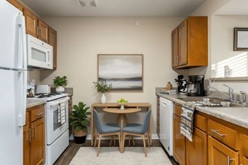 Wheeling apartment for rent - A kitchen with a white refrigerator, wooden cabinets, and a painting on the wall.