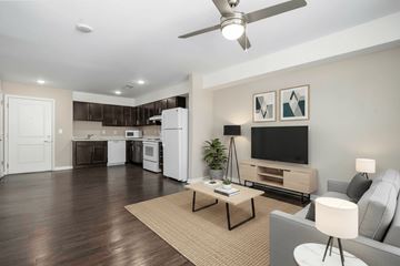 Statesville apartment for rent - A living room with a grey couch, a coffee table, a television, and a ceiling fan.