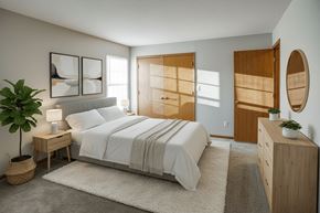 Monticello apartment for rent - A bedroom with a large bed, a nightstand with a lamp, and a plant on a side table.