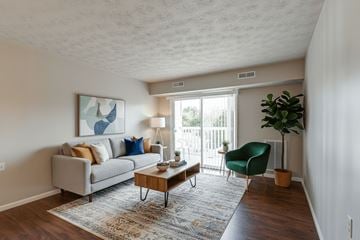Wintersville apartment for rent - A living room with a grey couch, a green chair, and a painting on the wall.