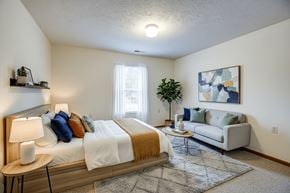 Wintersville apartment for rent - A bedroom with a bed, a couch, a table, and a painting on the wall.