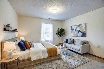 Wintersville apartment for rent - A bedroom with a bed, a couch, a table, and a painting on the wall.