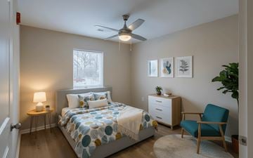 Zanesville apartment for rent - A bedroom with a bed, a chair, a nightstand, and a ceiling fan.