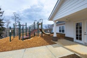 Zanesville apartment for rent - A playground with a slide and swings is in front of a house.