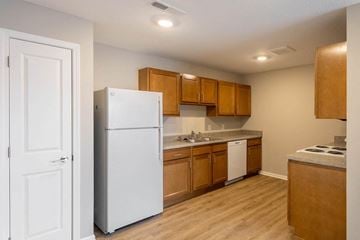 Zanesville apartment for rent - A white refrigerator stands in a kitchen with wooden cabinets and a white countertop.