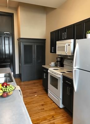Nelsonville apartment for rent - A kitchen with a white refrigerator, black cabinets, and a wooden floor.