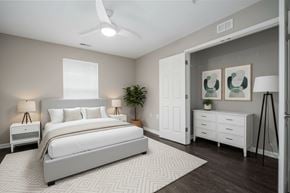 Charlotte apartment for rent - A bedroom with a large bed, a ceiling fan, and a plant.