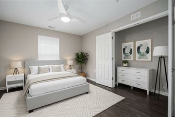 Charlotte apartment for rent - A bedroom with a large bed, a ceiling fan, and a plant.
