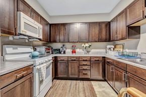 Dayton apartment for rent - a kitchen with dark wood cabinets and white appliances