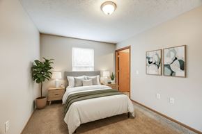 Coshocton apartment for rent - A bedroom with a bed, nightstands, and a plant.
