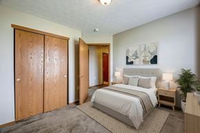 Orrville apartment for rent - A bedroom with a large bed and a plant on the nightstand.